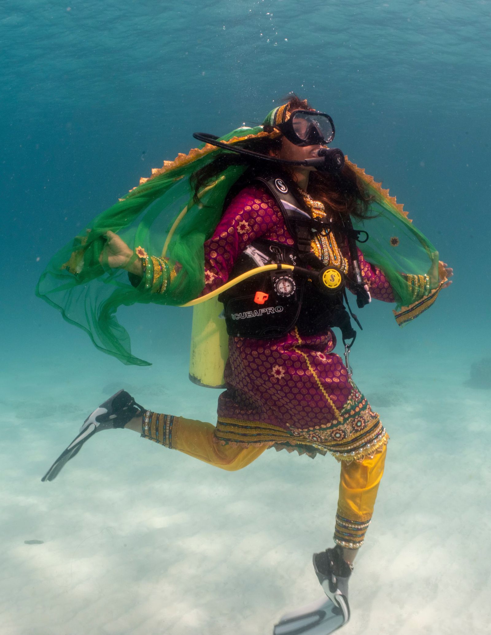 A solo female diver descending into deep blue water during an adventure dive.