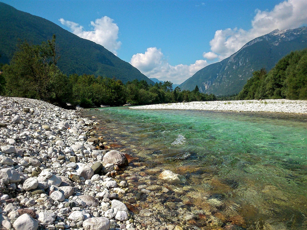 The crystal-clear emerald waters of the Soca River flowing through a lush valley.