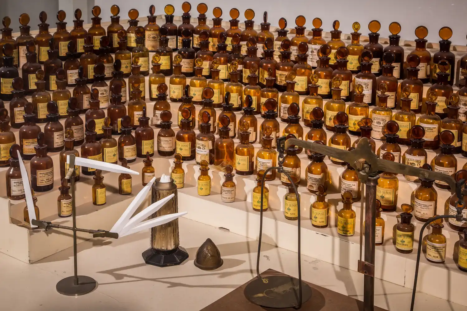 Antique glass perfume bottles and traditional perfumery tools displayed behind a glass exhibit in a museum.