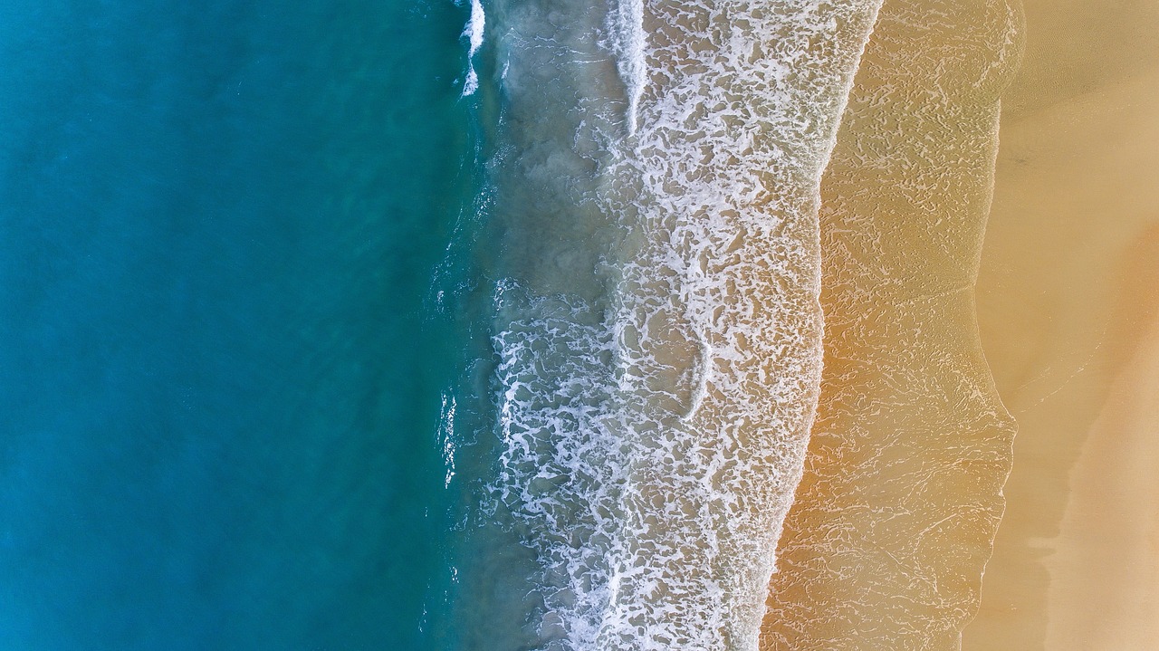 An aerial view of the curved Cape Cod peninsula surrounded by turquoise ocean water.