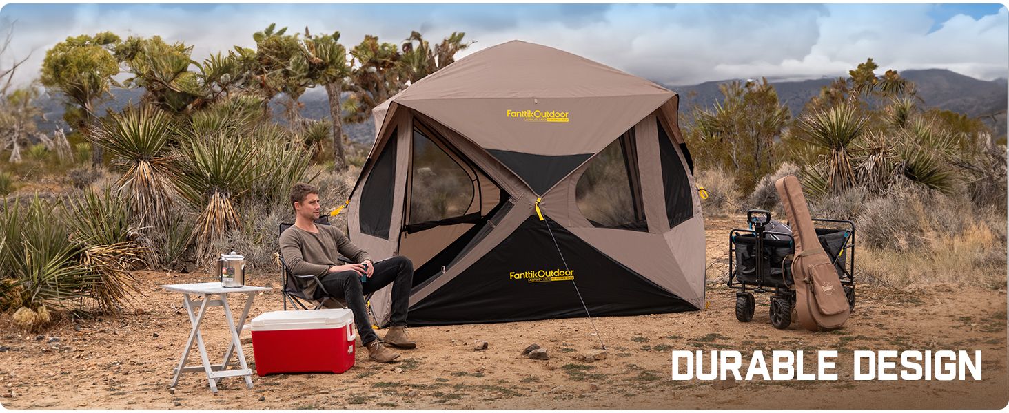A modern camping tent pitched in a mountain valley under a clear sky.