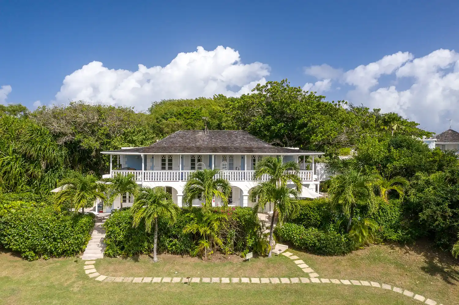 The two-story colonial-style exterior of the Cotton House suites surrounded by tropical gardens.