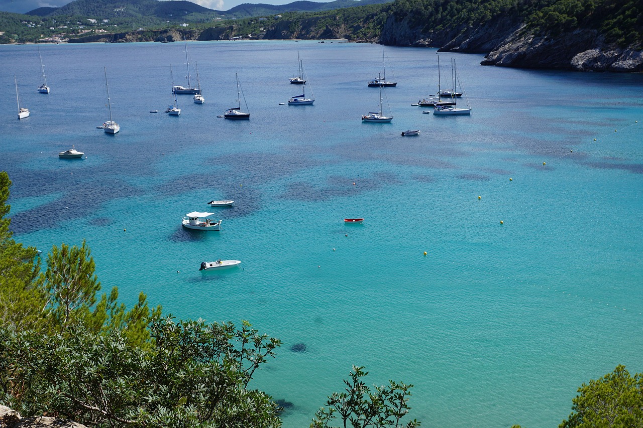 A white luxury yacht anchored in crystal clear shallow tropical water