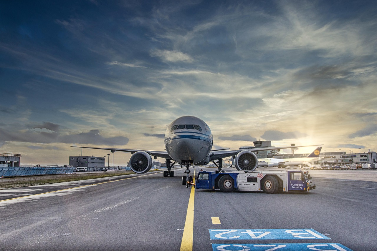 A woman with a backpack looking out of a large airport terminal window at planes on the tarmac