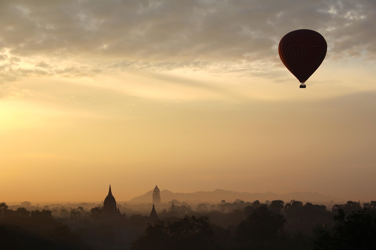 Several hot air balloons floating over the African savanna during a golden sunrise.