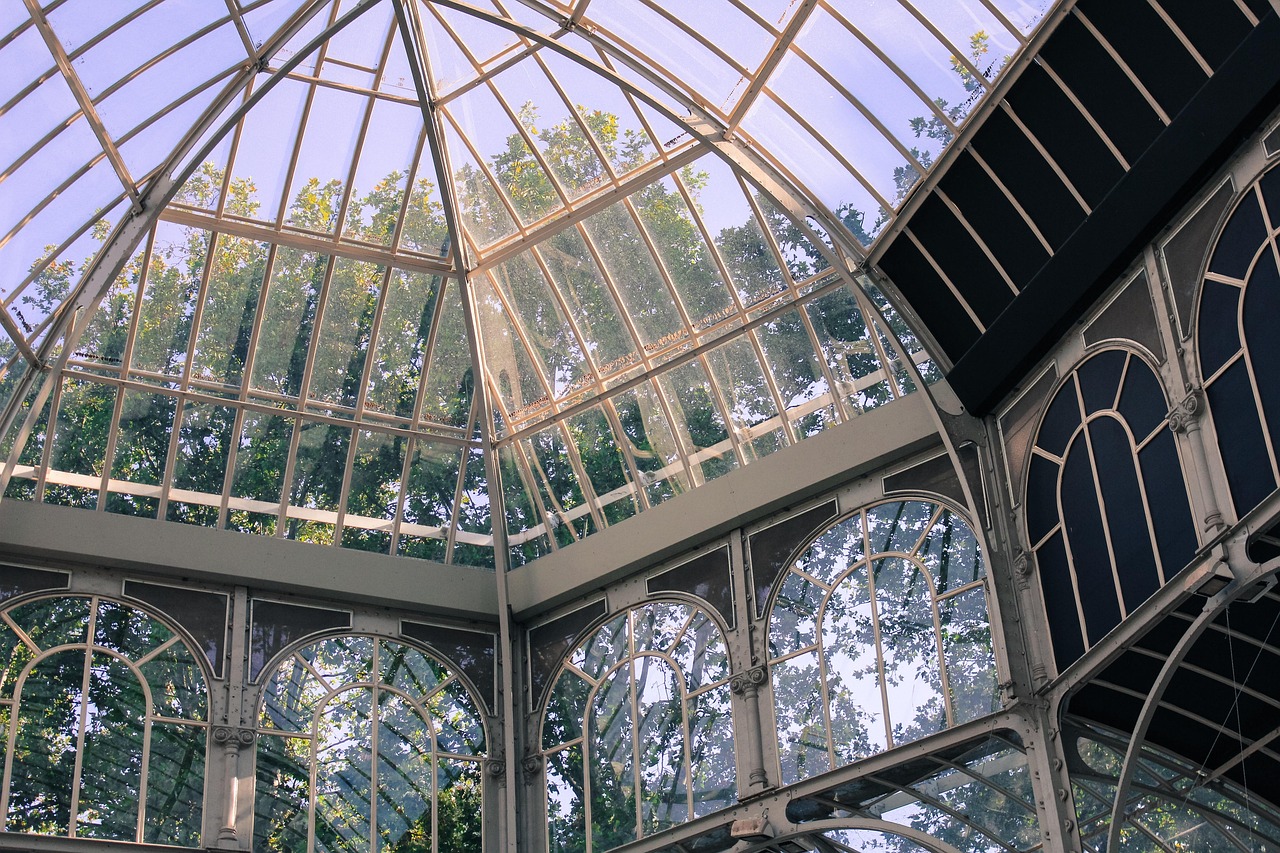 The glass-and-iron Palacio de Cristal surrounded by spring trees in Retiro Park.