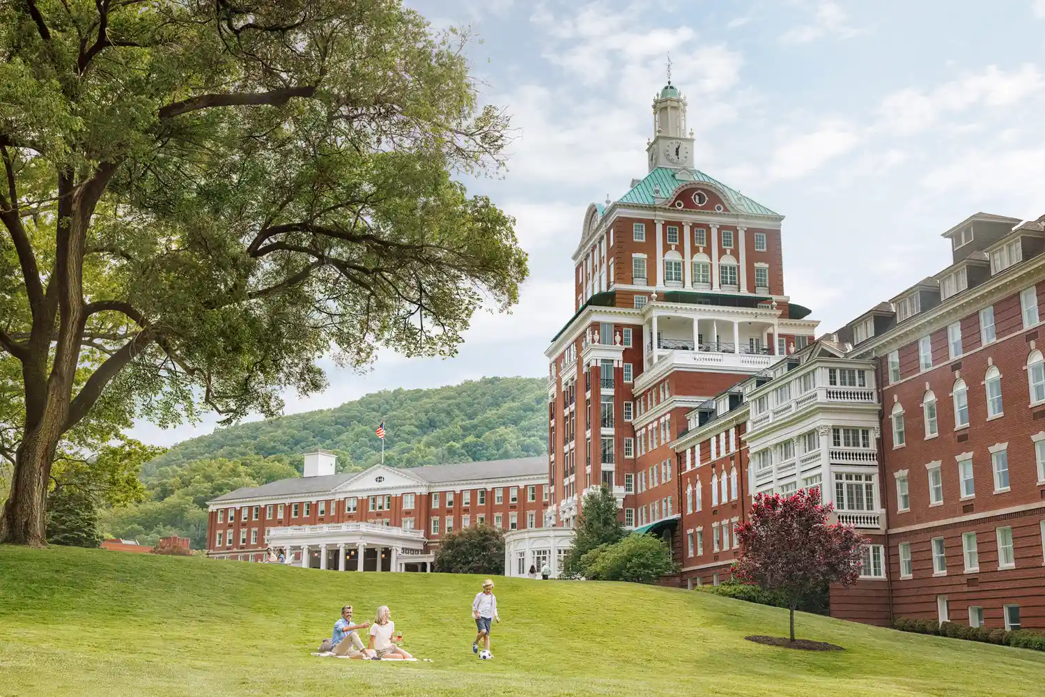 The exterior of the Omni Homestead Resort spa with guests on the lawn.