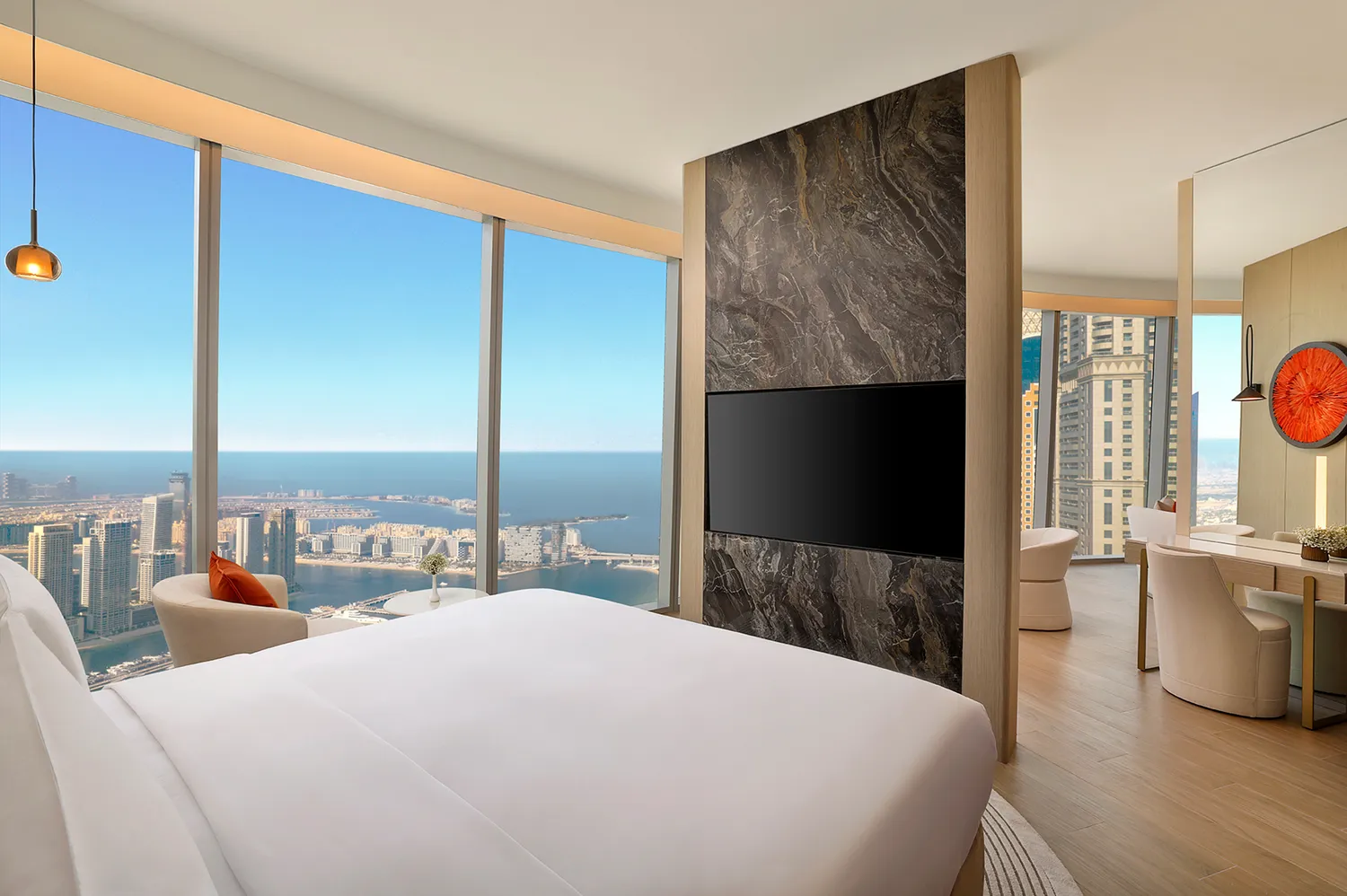 Interior of a luxury hotel suite with floor-to-ceiling windows showing the Dubai Marina skyline.