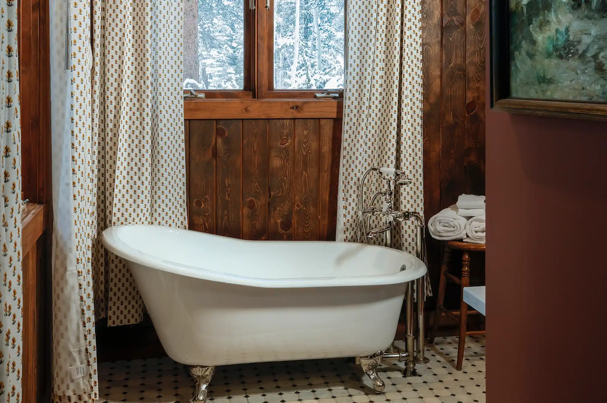 A white freestanding clawfoot bathtub in a rustic wooden bathroom.