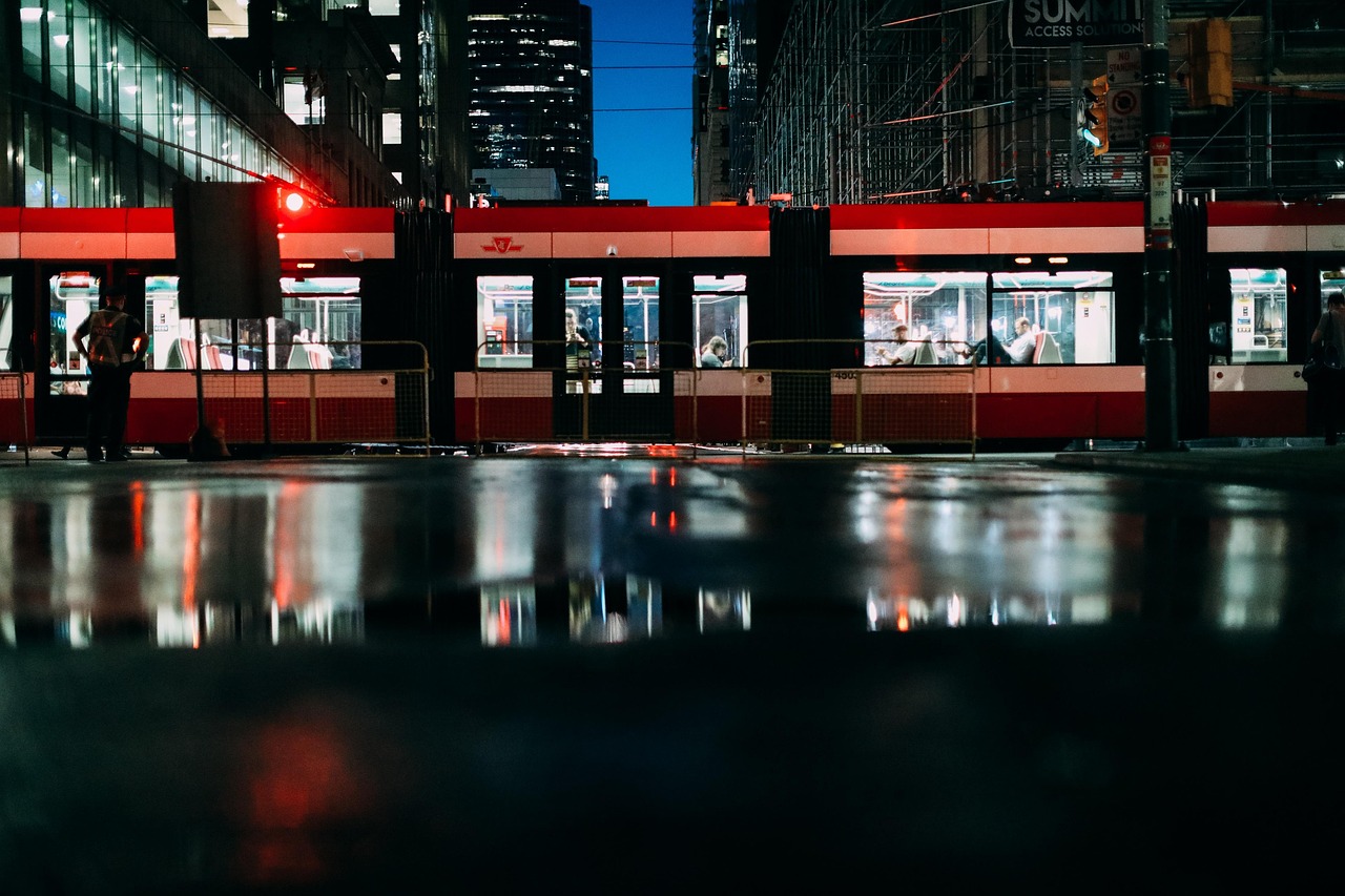 A classic red Toronto streetcar moving through a busy downtown street.
