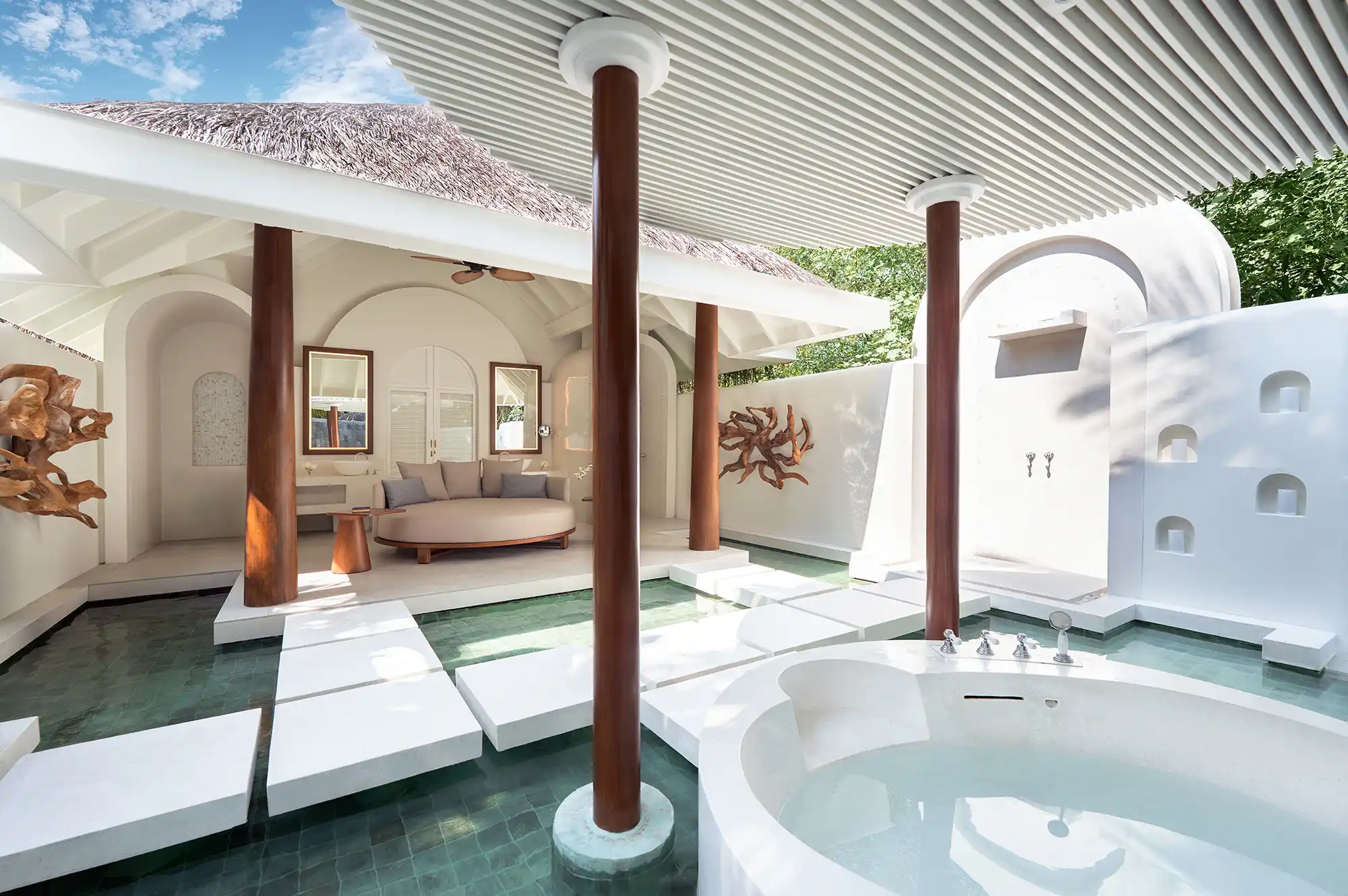 Luxury open-air bathroom with a round stone tub and tropical landscaping.