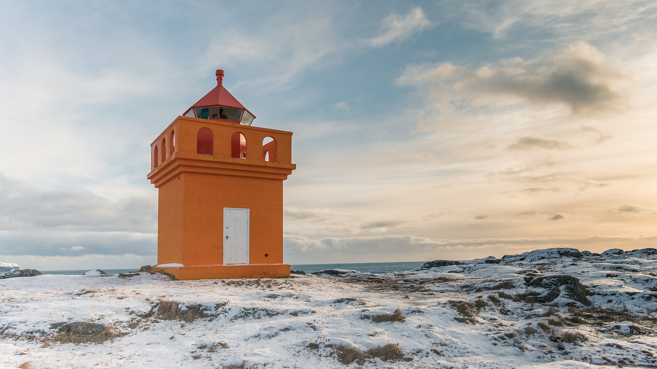 A lone lighthouse on a rocky cliff overlooking the Atlantic Ocean in Iceland