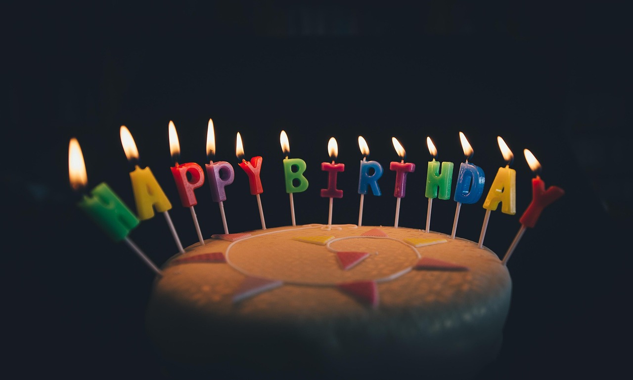 A small chocolate birthday cake with a lit candle being served at a dinner table.