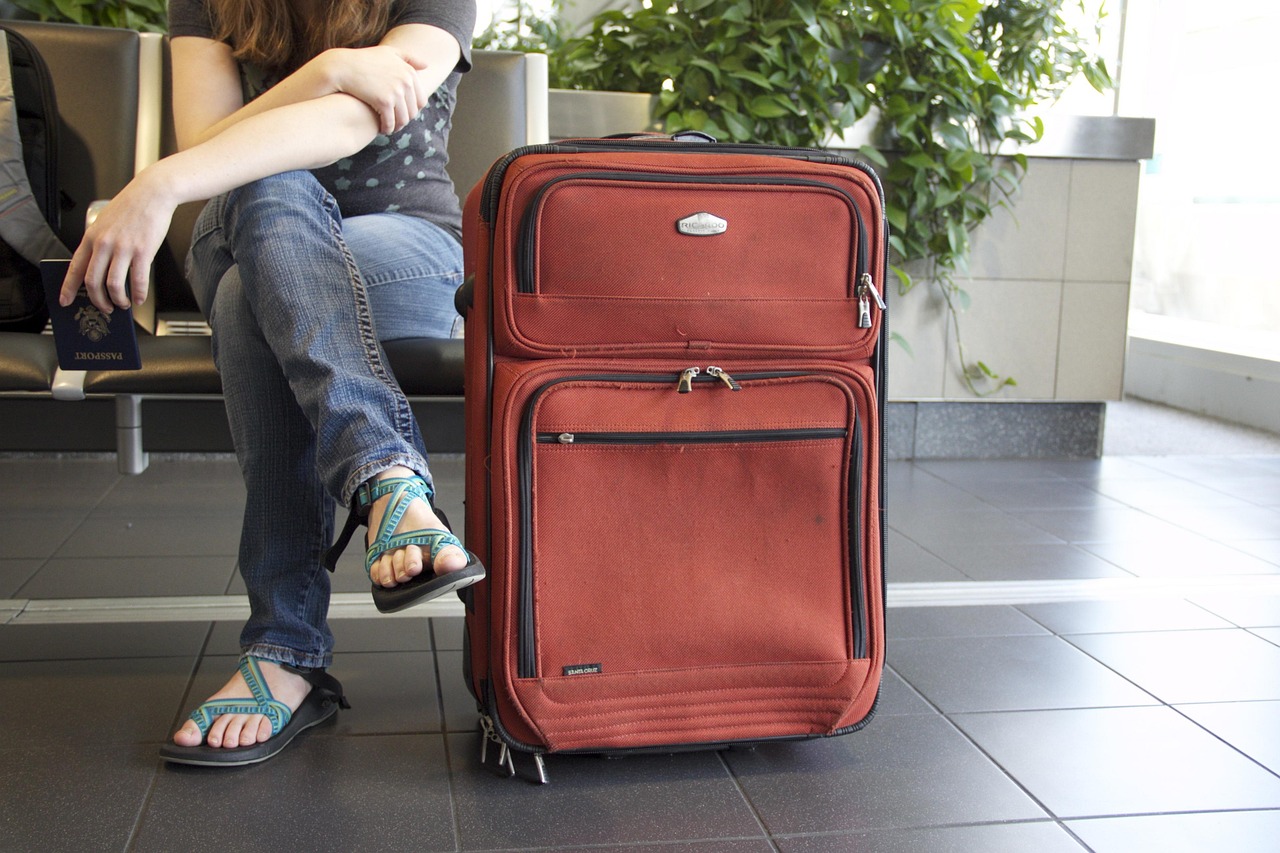 A neatly packed suitcase with a passport and travel accessories on a wooden floor