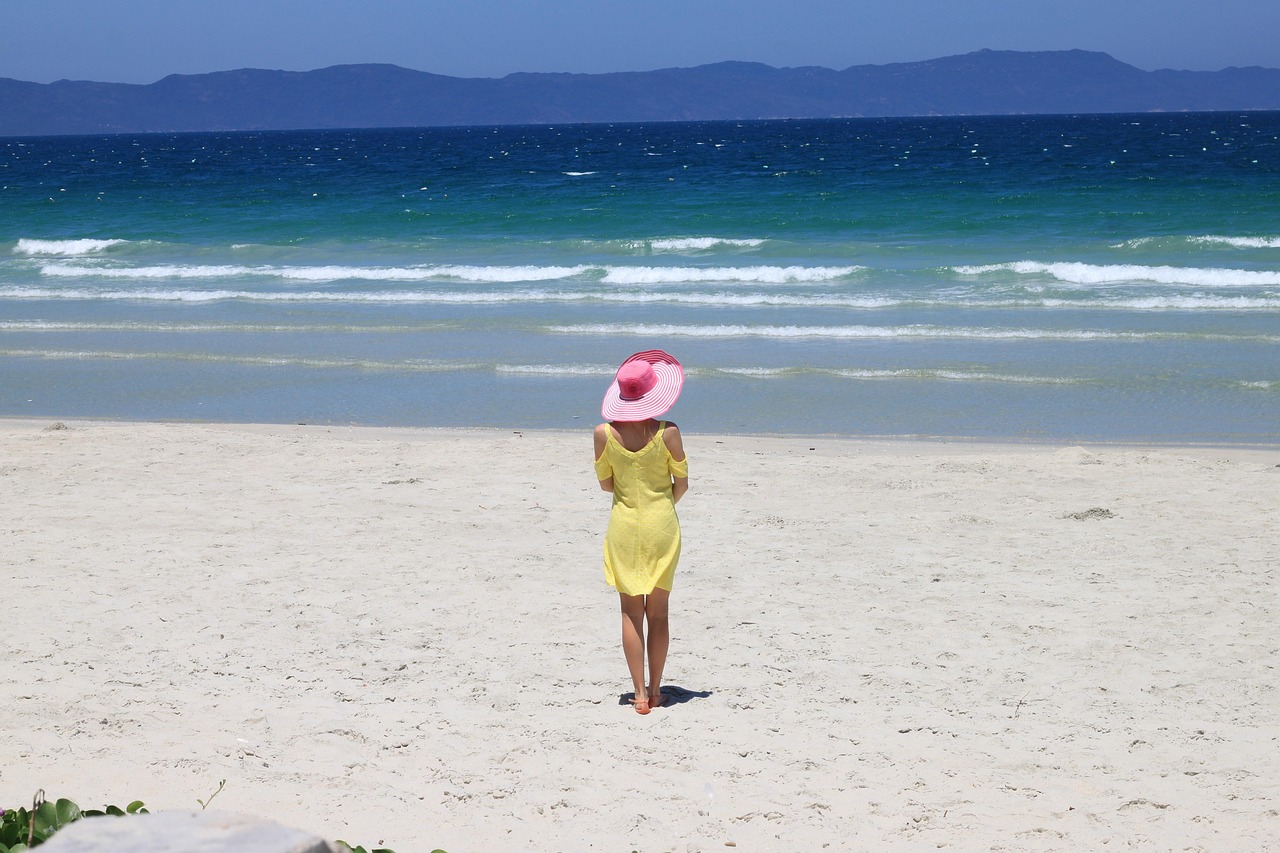 Elegant woman wearing a wide-brimmed straw hat overlooking the Italian coastline.