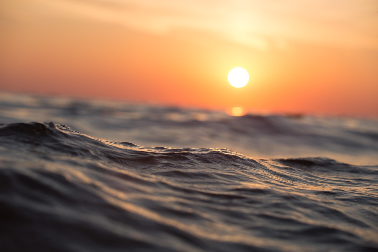 A peaceful, wide shot of the ocean meeting a clear blue sky at dawn.