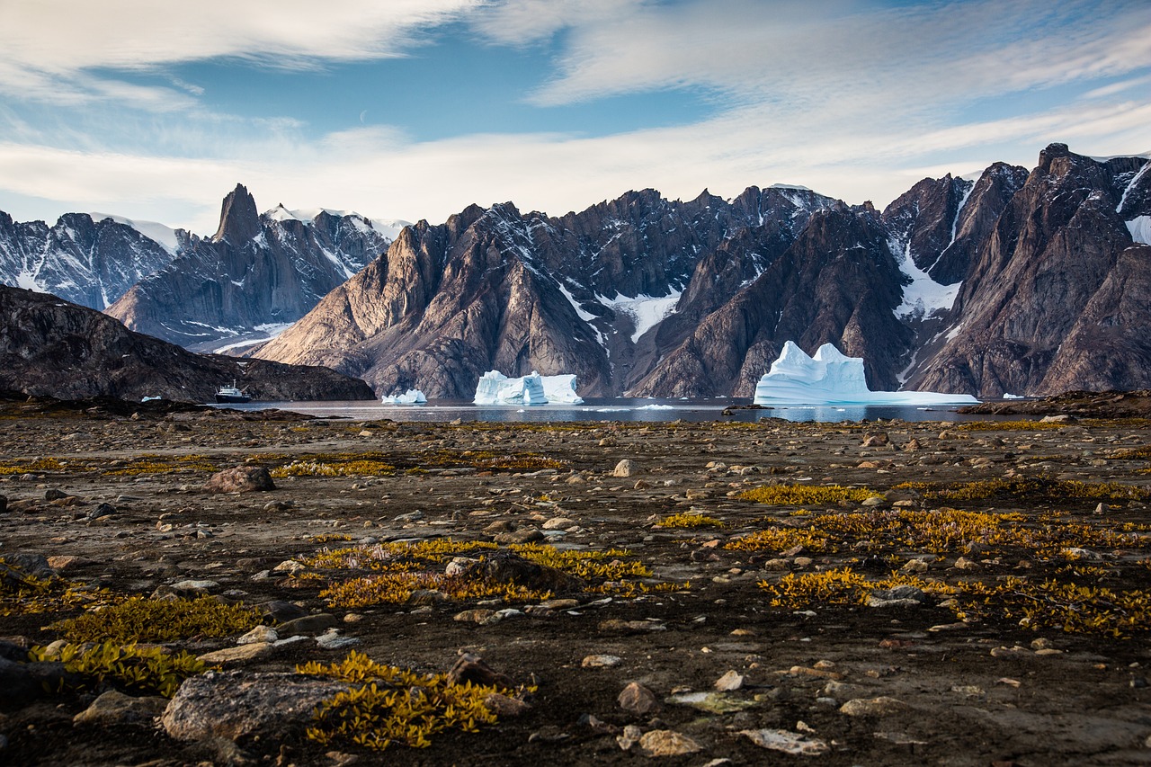 A modern expedition cruise ship navigating through a channel filled with icebergs.