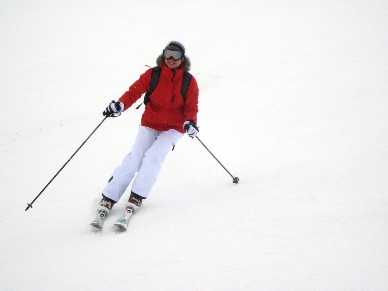 A professional female skier carving through deep powder on a steep mountain slope