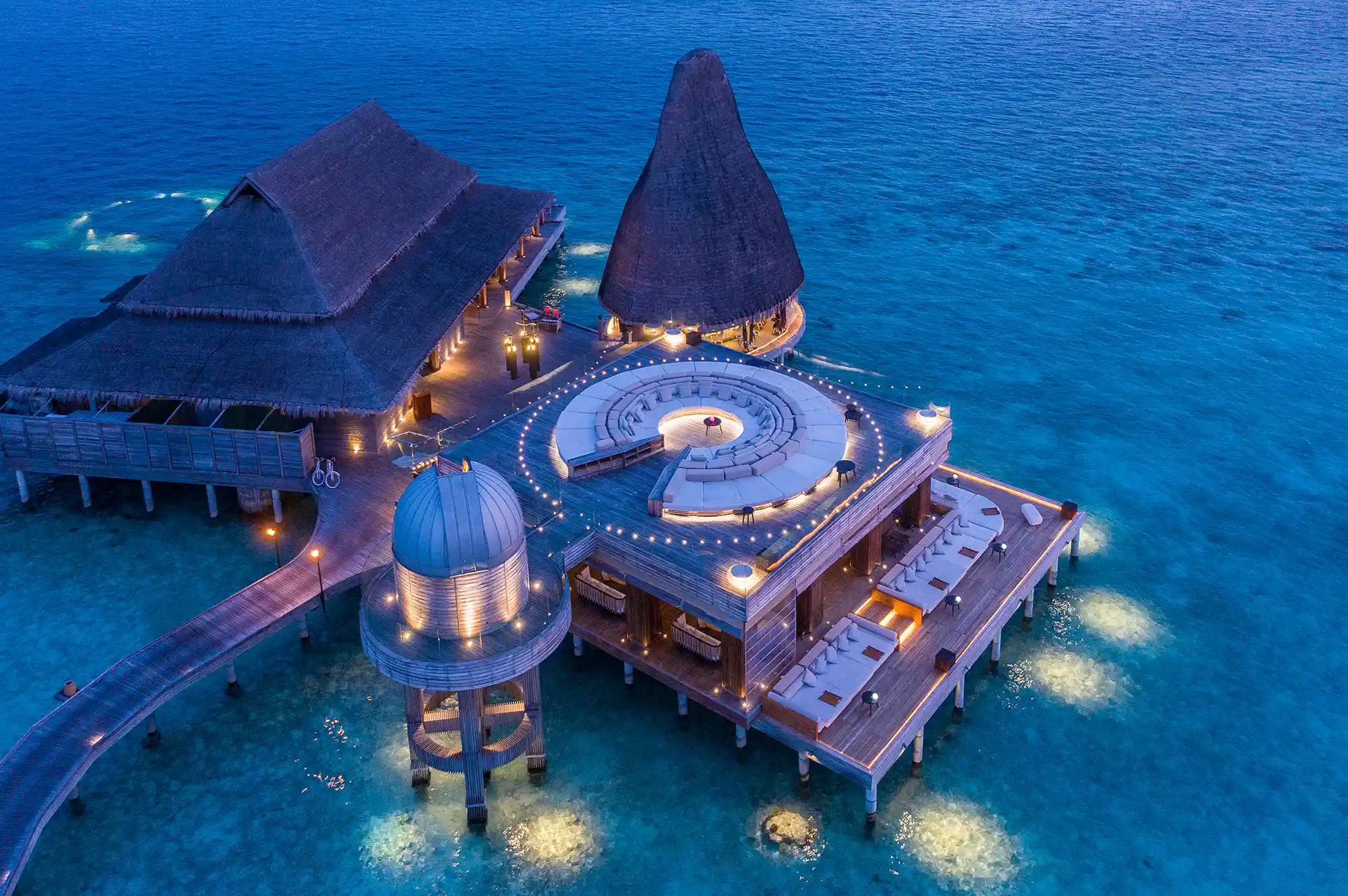 Aerial view showing the transition from shallow turquoise water to the deep blue ocean near the resort buildings.