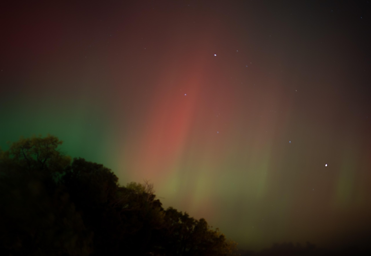 The green aurora borealis dancing over a snowy forest and a glass igloo