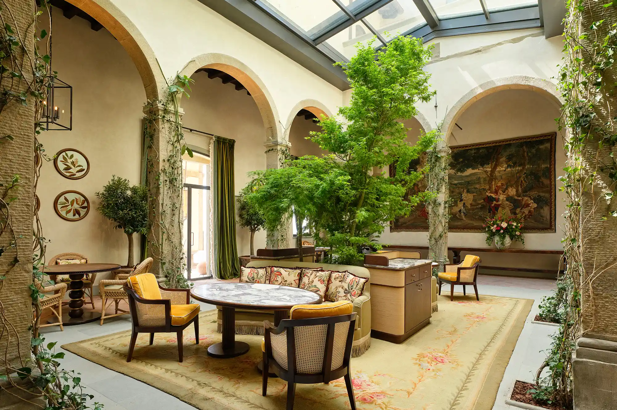 The internal historic cloister of Villa San Michele featuring elegant arches and a glass-enclosed ceiling.