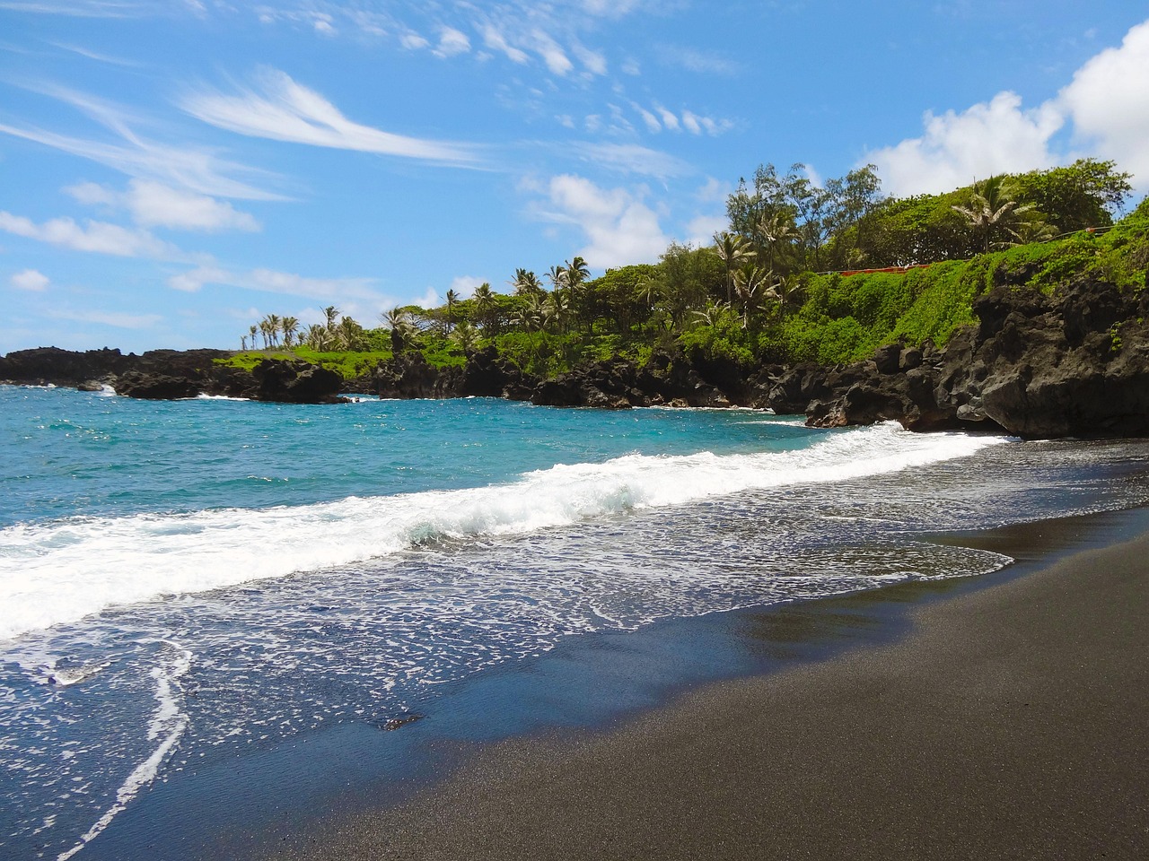 A lush green Hawaiian coastline meeting the deep blue Pacific ocean.