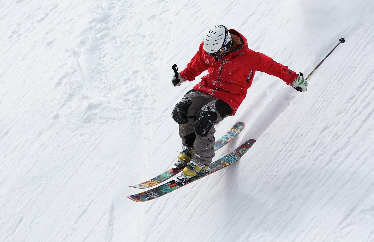 A skier making a turn on a wide, groomed mountain run with mountains in the background
