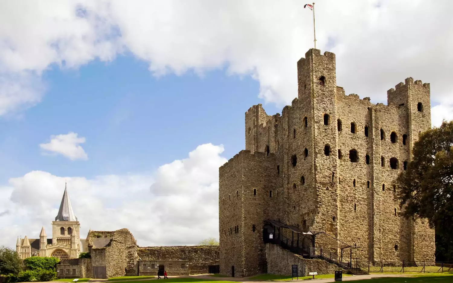 The towering square keep of Rochester Castle against a blue sky.