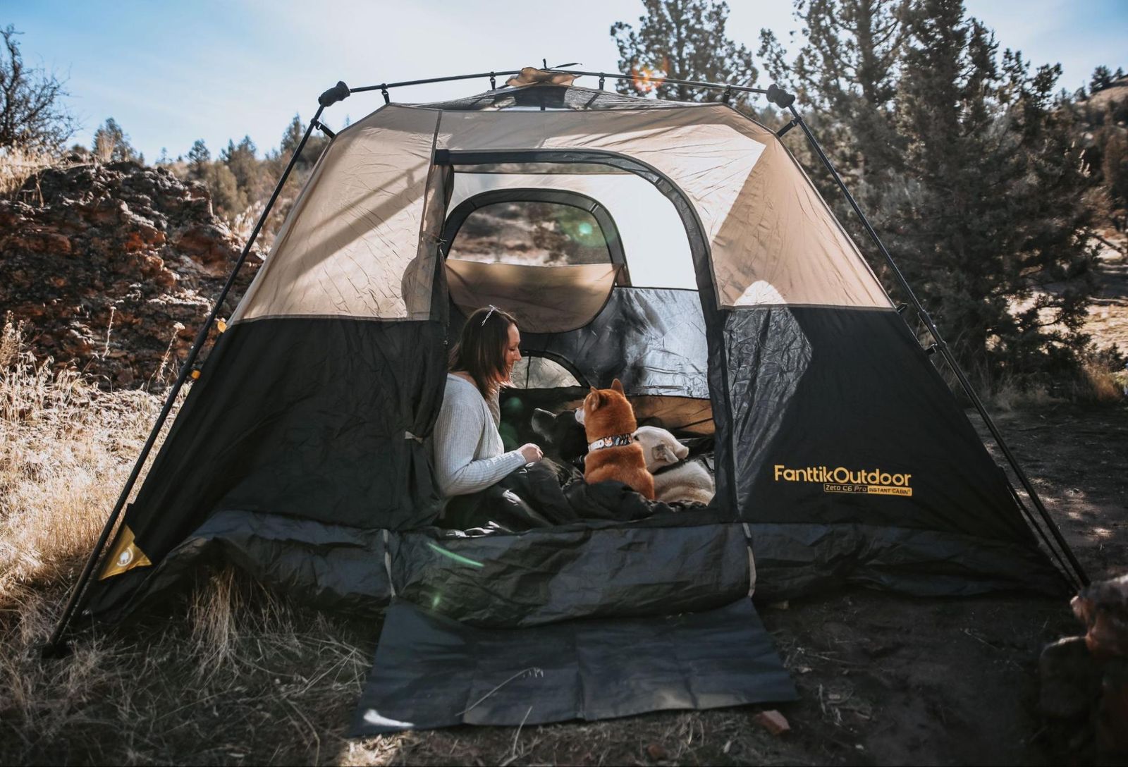 A camper and their dog relaxing outside a large, spacious camping tent.