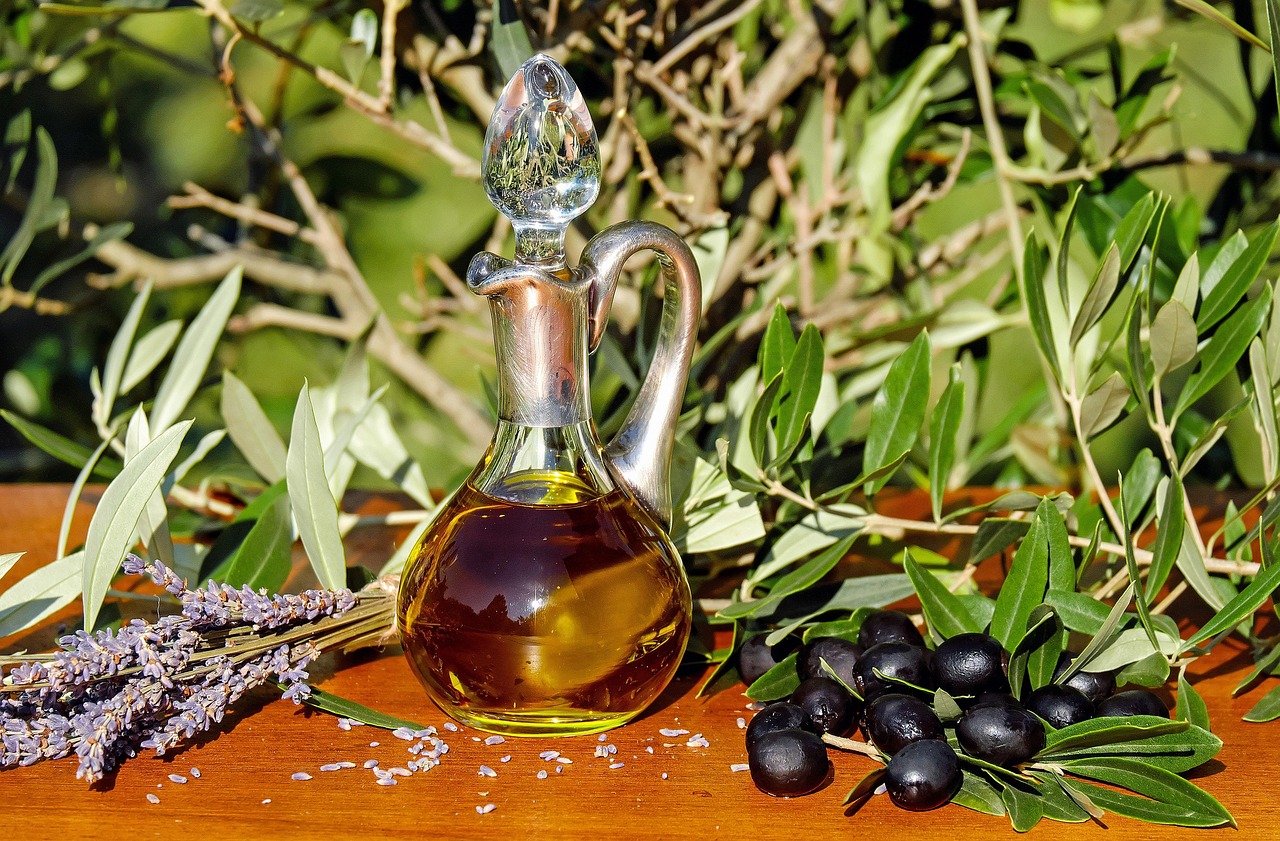 Fresh green olive oil being poured onto crusty bread on a wooden table.