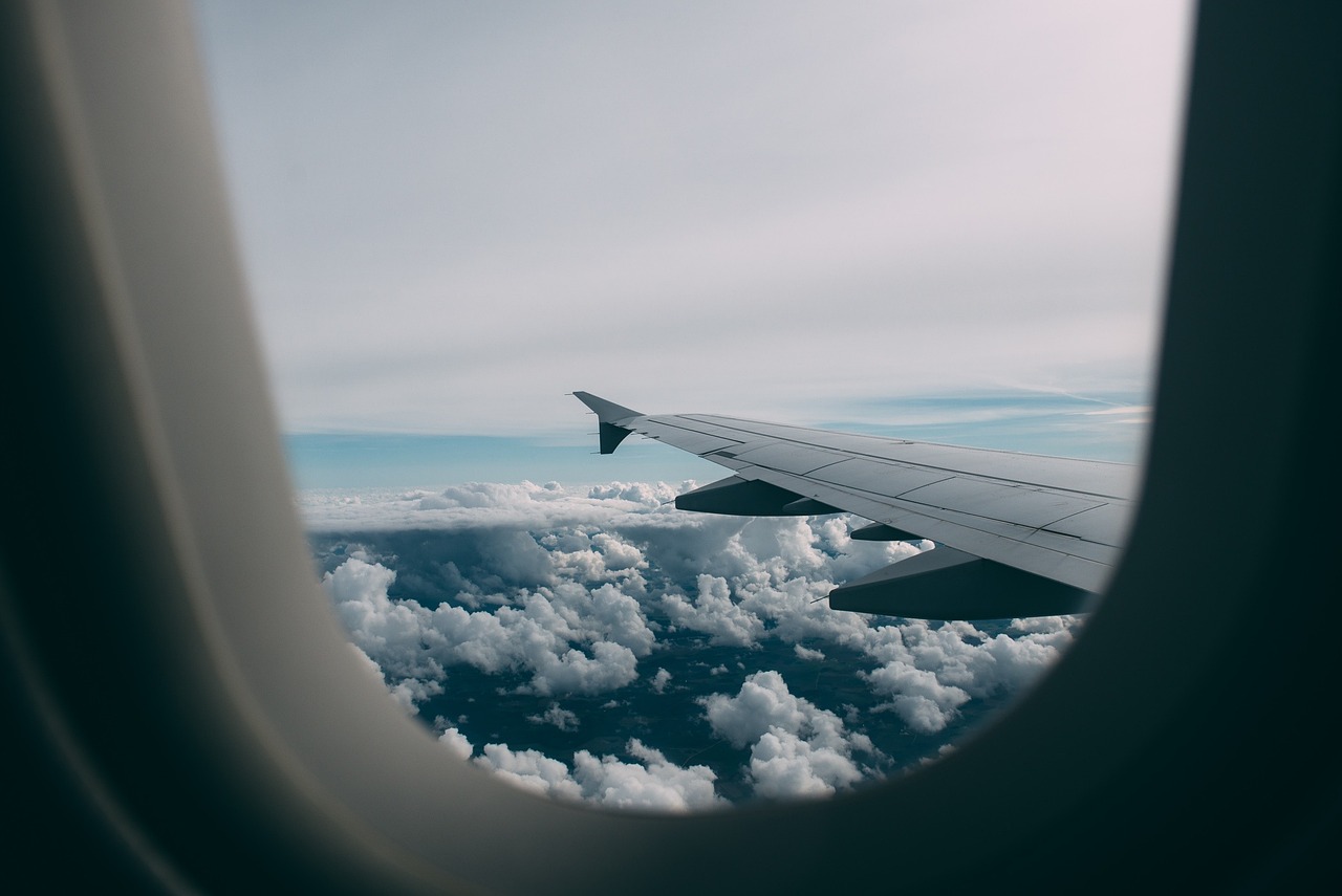 View of an airplane wing flying above a sea of clouds.