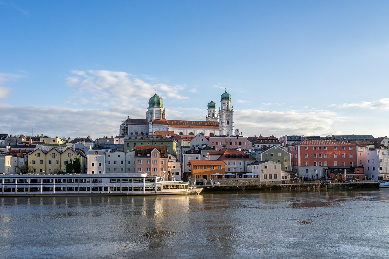 A luxury river cruise ship sailing past a historic European town on a sunny day.