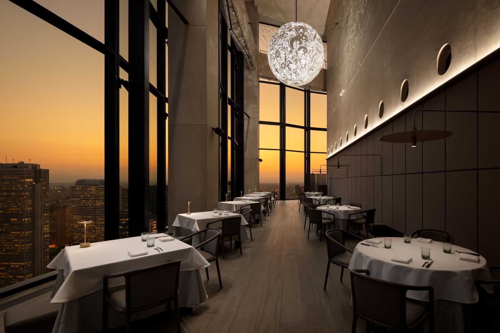 A high-end restaurant dining room with set tables overlooking the Tokyo city skyline.