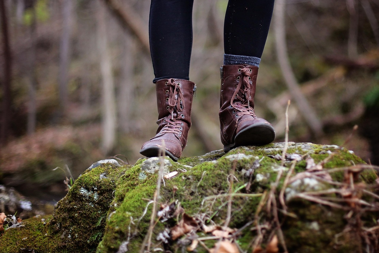 A young child with a small backpack walking on a forest path.
