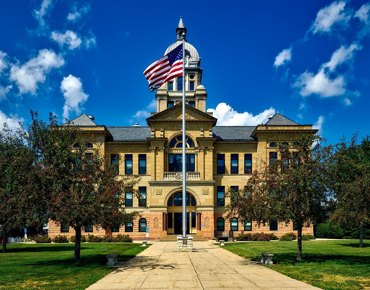 An American flag waving in front of a colonial-style brick building.