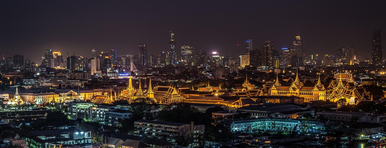 A lush green park in front of the Bangkok city skyline.