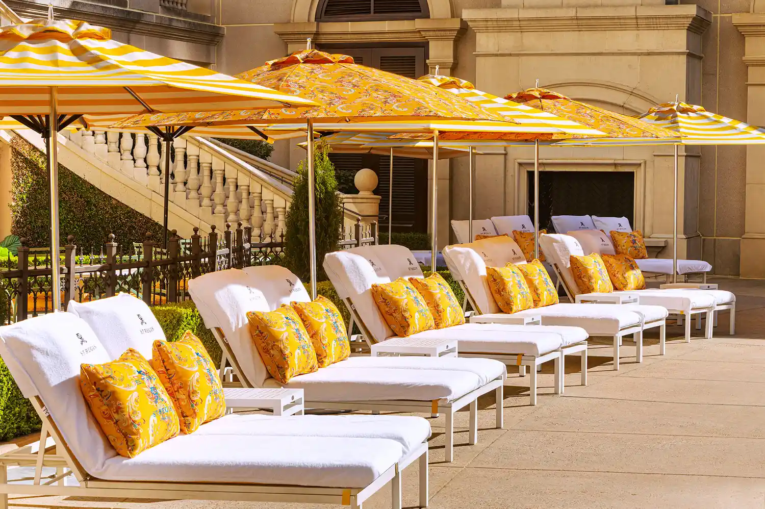 Luxury lounge chairs with Etro cushions and yellow umbrellas arranged around the pool terrace.