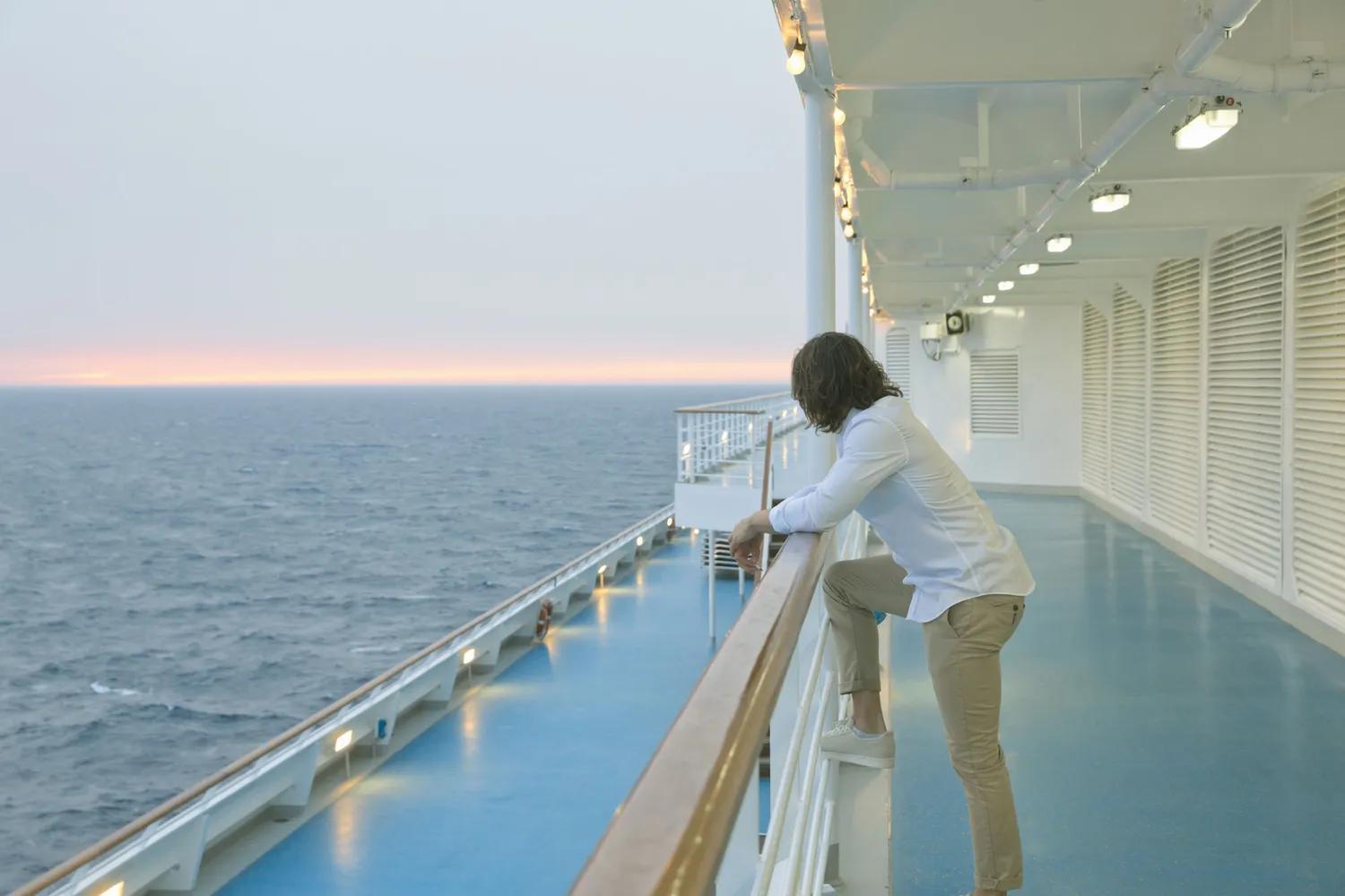 A lone traveler standing by the ship's railing looking out at the horizon.