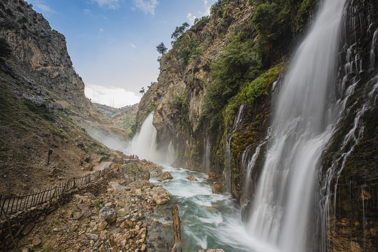 A massive, multi-tiered waterfall cascading down a rugged sandstone cliff face.