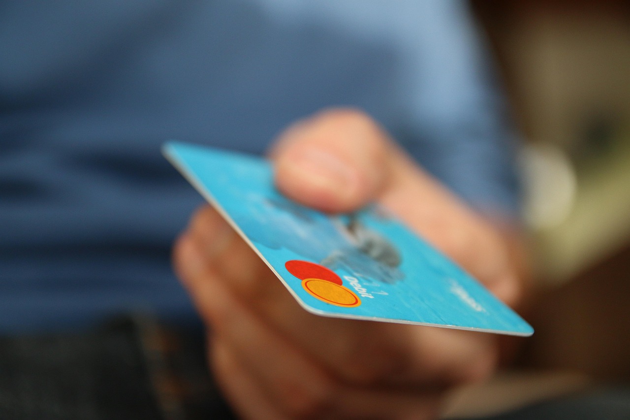 A hand holding a premium credit card against a blurred travel or airport background.